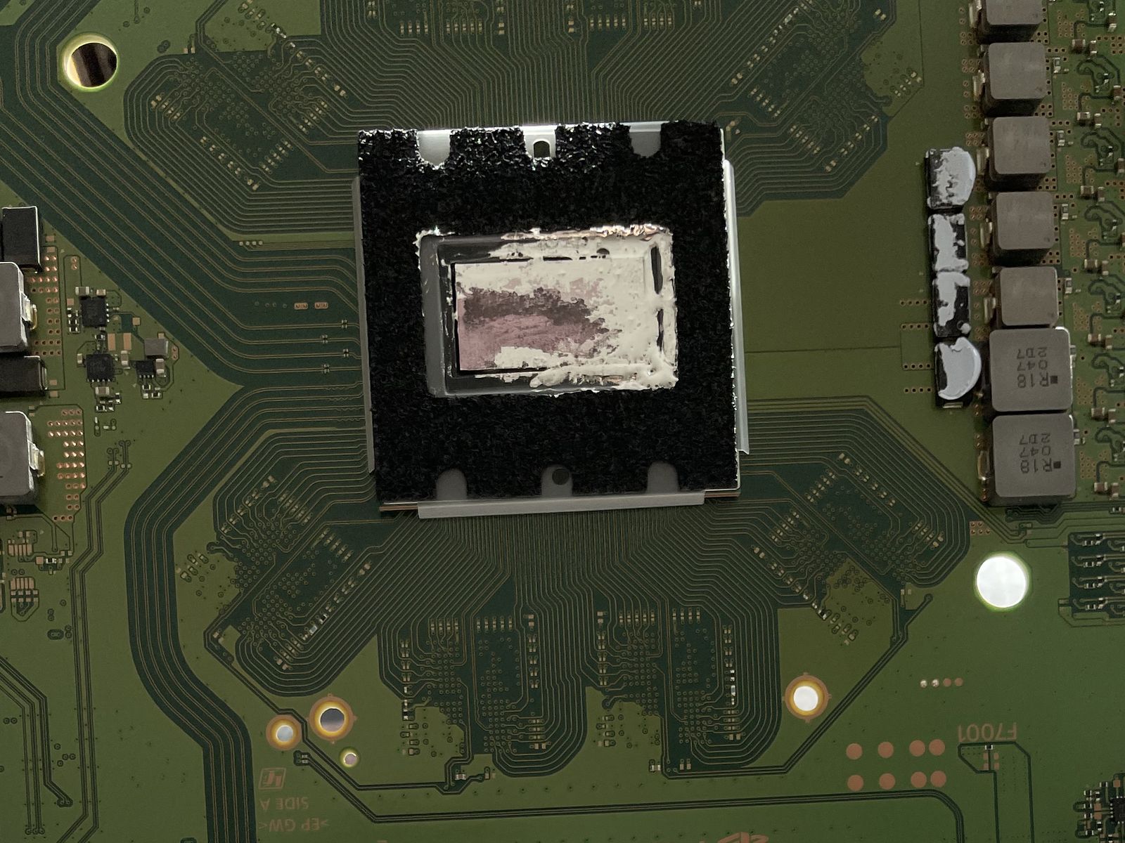 PS5-moederbord met de processor binnen de schuimrand en het oude, dof geworden vloeibaar metaal